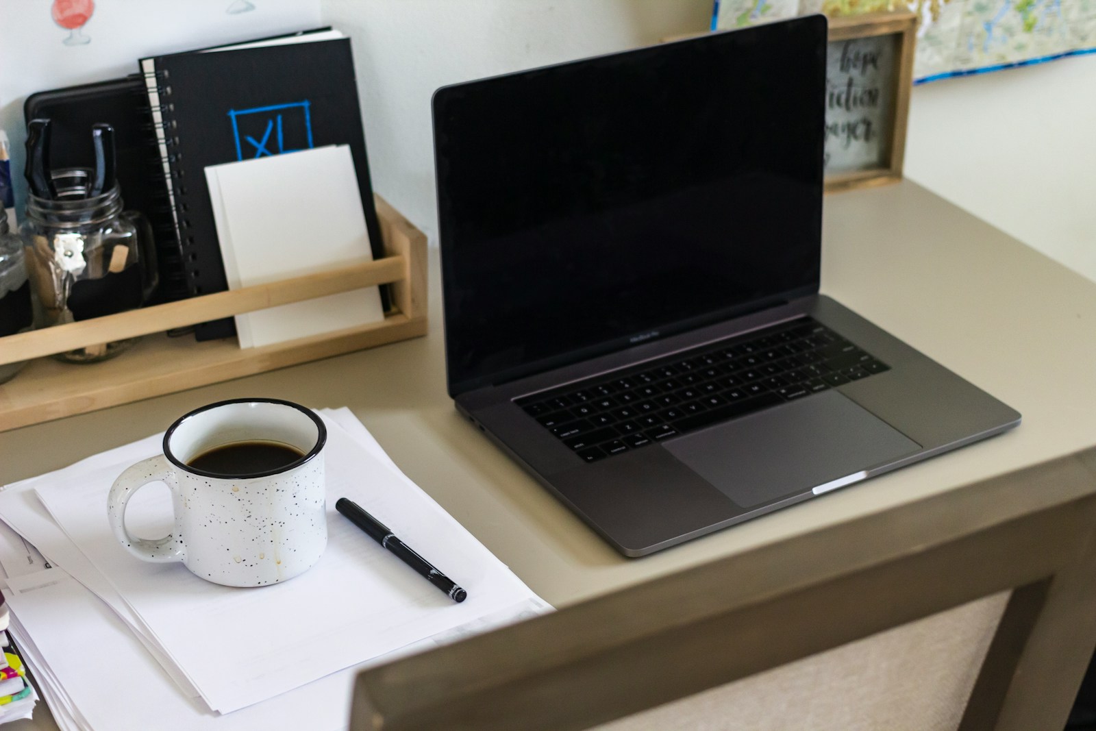 black laptop computer beside white ceramic mug on white table